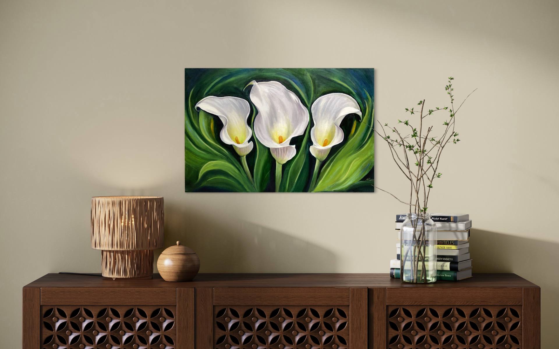 Oil painting of three white calla lilies set on a background of swirling green leaves displayed above a wooden cabinet with books and trinkets on