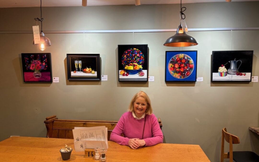 exhibition at the Nest Little Verzons Farm Ledbury view of five paintings with artist Nicola Currie sitting in front of them
